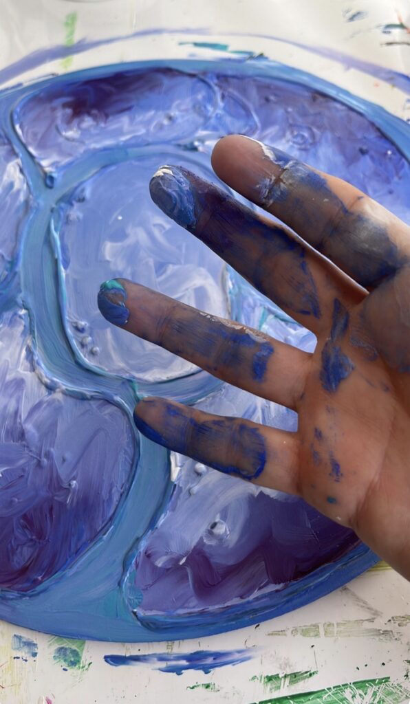 Hand mit blauer Farbe beim intuitiven Malen