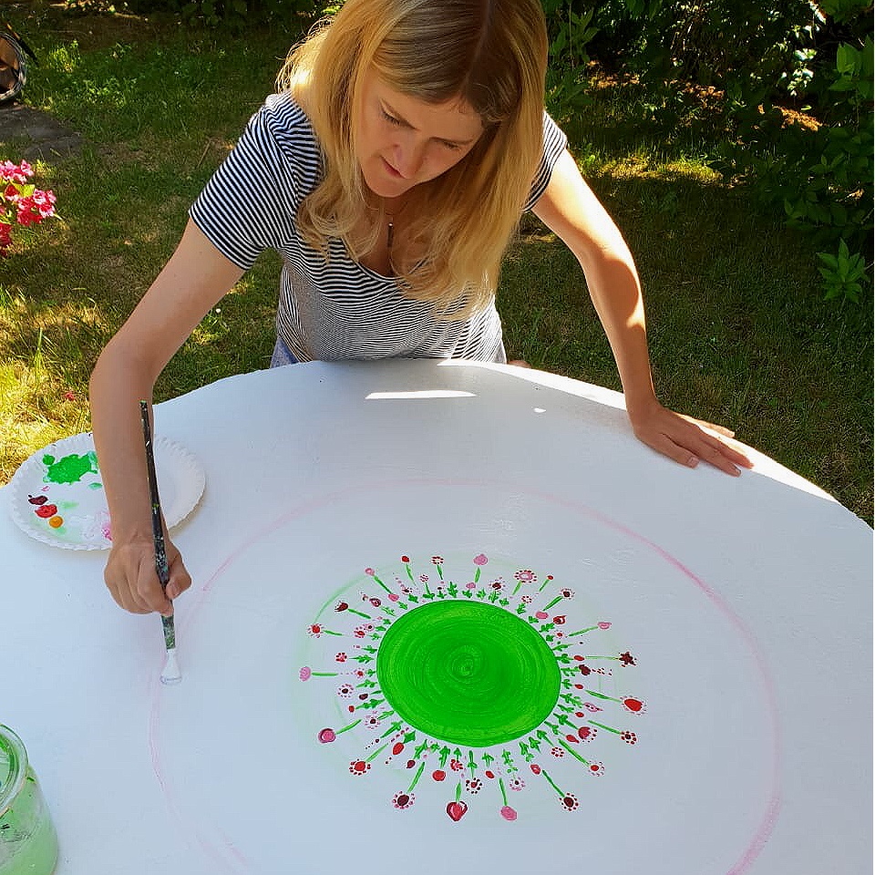 Doreen Gündel malt ein farbenfrohes Mandala im Garten